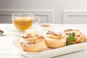 Freshly baked apple roses with mint, honey and tea on white marble table, closeup