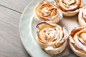 Freshly baked apple roses on wooden table, closeup