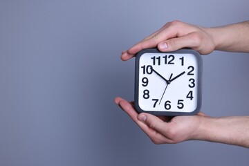 Man with alarm clock on grey background, closeup. Space for text