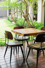 Wooden table and chair set in garden on a sunny day,outdoor seating for restaurant or cafe,Neat paved patio with sitting area and small garden in forest..