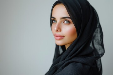 Naklejka premium Happy young woman in black hijab posing sideways.