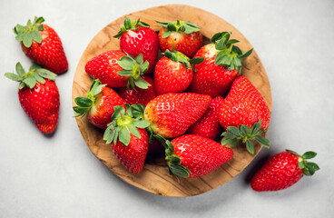 Strawberry, fresh ripe organic strawberries in a wooden bowl close-up. Strawberries on a gray table background. Fresh ripe strawberries, macro shot of fresh juicy berries, close up, top view