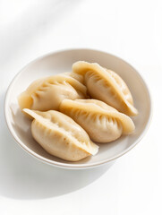 Delicious homemade dumplings served in a white bowl on a light background