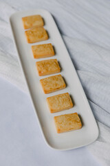 Delicious array of perfectly baked rectangular cookies arranged on a long white platter with a simple backdrop