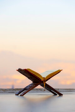A serene moment of faith. A Quran and prayer beads rest against a backdrop of a tranquil nature scene, with a minaret subtly placed in the distance.