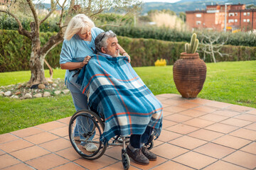 Compassionate Nurse Assisting Elderly Man in Wheelchair Outdoors