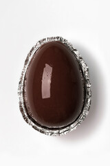 Chocolate egg in foil on white background, chocolate easter egg, top view