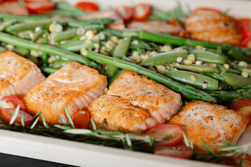 Oven-roasted salmon with fresh vegetables on a wooden serving platter