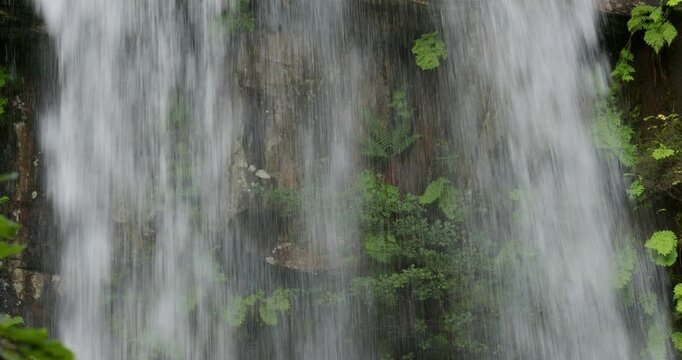 Shot looking though the Melin Court waterfall at the rocks and ferns behind the waterfall.