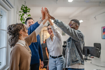 Positive motivated multicultural colleagues raise their hands together