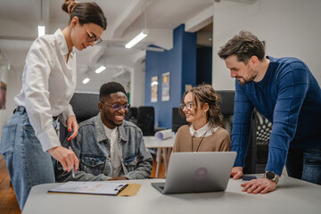 multicultural colleagues work together on laptop in the office