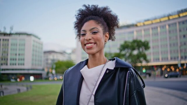 Gorgeous girl strolling street with wind blown curly hair closeup. African woman
