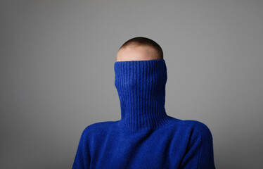 Young woman wearing casual blue jersey covering her head posing indoor. Vertical mock-up.