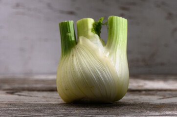 Unique close-up of a fresh fennel bulb on rustic wooden surface during afternoon light