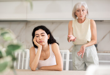 Elderly woman during family quarrel with young woman in kitchen at home