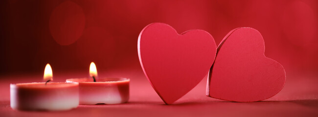 Two red hearts aligned with glowing candles create a romantic and affectionate scene set against a dazzling red background, symbolizing love in modern art style.