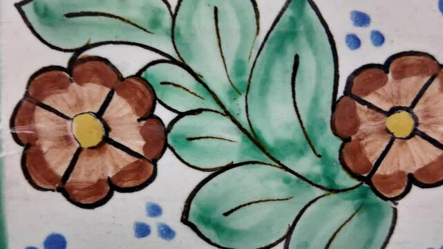 A green and brown flower design is painted on a white background
