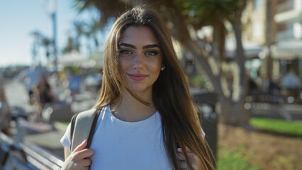 Woman standing confidently on sunny urban street, brunette hair flowing, youthful charm radiating,...