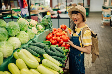 Asian woman shopping for tomatoes at an outdoor market stall