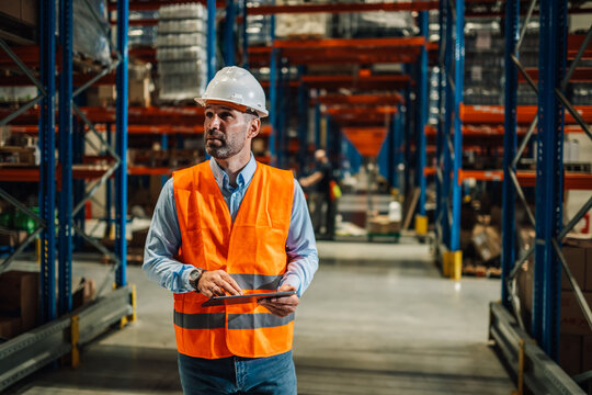 Warehouse manager using digital tablet checking goods and supplies on shelves - Powered by Adobe