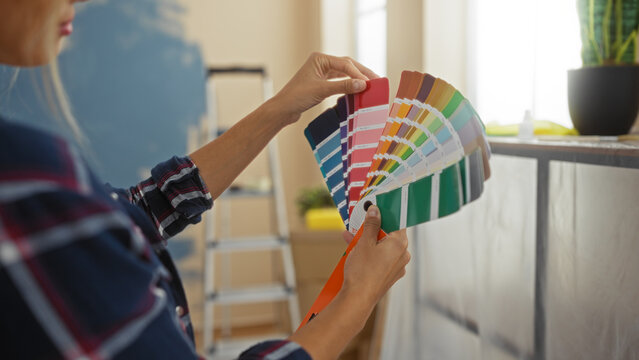 Woman choosing paint colors in modern, bright living room, showcasing creative home decor with vibrant swatches, stylishly reflecting interior design trends for apartment renovation.
