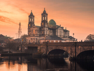 View on Church of Saints Peter and Paul at sunset. Warm color light. Cloudy sky reflects in river...