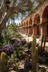 outdoor walkway in mission of San Juan Capistrano with desert plants in foreground