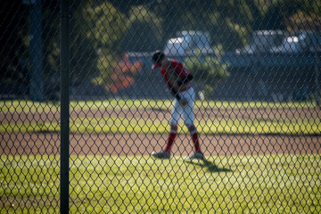 out of focus figure of athlete in baseball field  behind fence