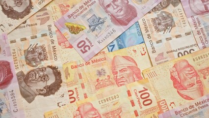 Mexican pesos banknotes scattered, showcasing various designs and denominations from the bank of mexico.