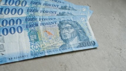 Hungarian thousand forint banknotes scattered on a concrete surface showcasing traditional hungarian currency.