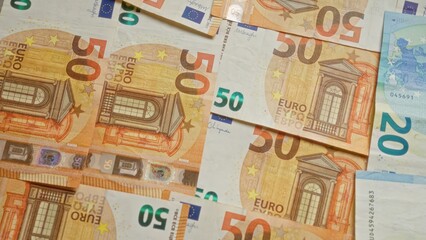 Euro banknotes scattered across a surface, showcasing various denominations prominently including 50 and 20 euros, representing european currency, finance, and economic concepts.
