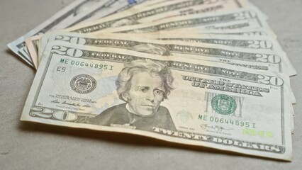 United states twenty-dollar banknotes spread out on a concrete surface, highlighting american currency in a neutral setting.