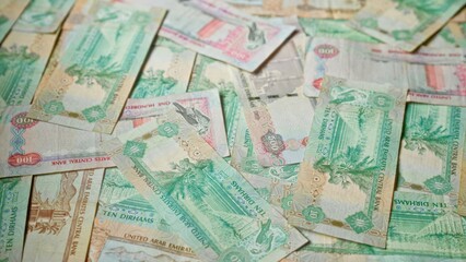 Uae dirhams scattered in various denominations highlighting the vibrant banknotes of the united arab emirates's currency in a detailed close-up shot.