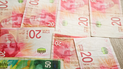 Israeli currency including shekels scattered on a table, showcasing various denominations and...