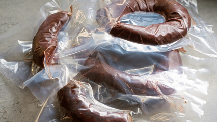 Vacuum-packed sausages displayed on a gray surface showcasing food preservation and packaging methods for fresh meats