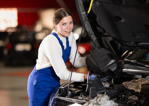 Female mechanic checks the car and carries out maintenance. Professional mechanic checks the engine and oil under the hood of the car