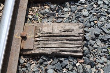 close-up macro rotting wooden railway tie and rusting iron spike securing the rail