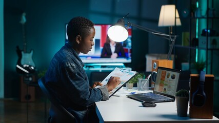 African american woman working from home, using laptop, looking at statistic charts. Remote worker...