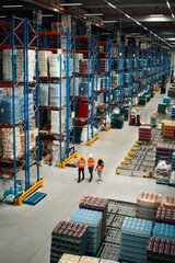 Fototapeta premium Warehouse workers walking and controlling inventory in large distribution center