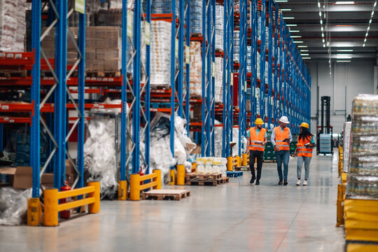 Warehouse workers walking and discussing logistics in a storage facility
