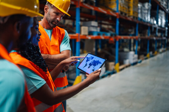 Warehouse workers checking global logistics on digital tablet - Powered by Adobe