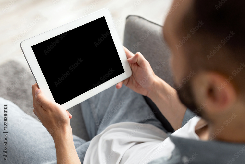 Poster unrecognizable young guy working on tablet computer with empty screen at home office, mockup for web