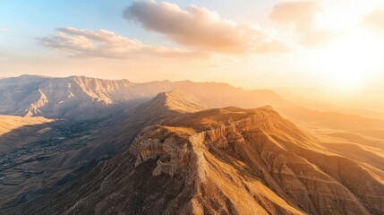 Fototapeta premium A breathtaking aerial view of rugged mountains at sunset, showcasing golden hues and valleys below