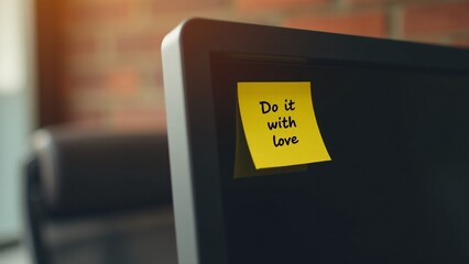 A yellow post-it with "Do it with love" on a coworking space screen, with exposed brick and ergonomic leather chair, inspiring passion and dedication.
