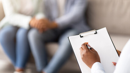Closeup of black married couple and psychotherapist at office after effective session, selective focus. Unrecognizable spouses holding hands after successful consultation with psychologist, copy space