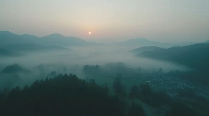 Naklejka premium Serene sunrise over misty mountains with a tranquil village nestled in the valley