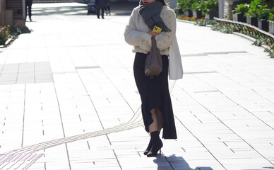 冬の都市の繁華街で信号待ちの若い女性の姿