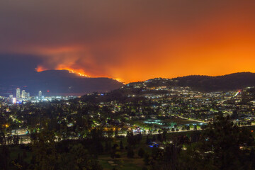 A wildfire burns on a mountainside near Kelowna illuminating the night sky with an orange glow...