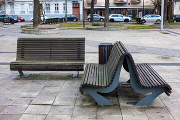 Double and regular wooden benches in the city park. A place to relax in the city.