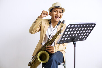 Young Asian Man Celebrating Achievement After Making A Song With Saxophone 
